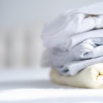 stos damskich kolorowych bluz bluz w pastelowych kolorach na bialym lozku sezonowe zakupy pralnia koncepcja wakacji