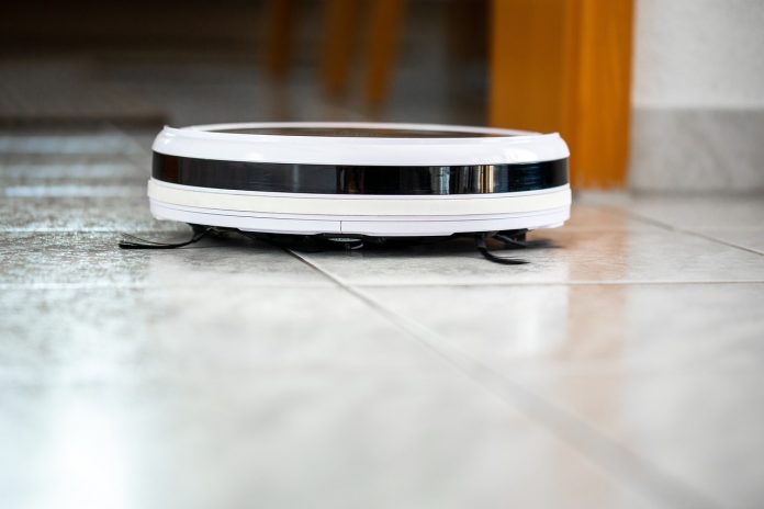 Autonomiczny odkurzacz Roomba krąży po domu, zbierając kurz i okruszki z podłogi